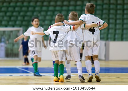 Indoor football soccer match for children. Happy kids together after winning futsal game. Children celebrate sport victory. Youth sport triumph in futsal. Futsal indoor soccer tournament for kids Royalty-Free Stock Photo #1013430544
