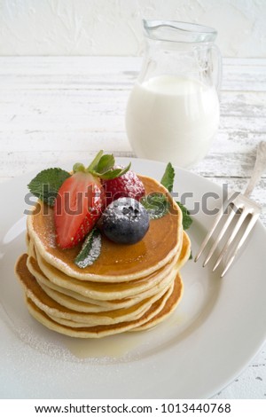 American pancakes with berries on a light background.