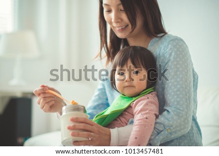 Pretty japanese woman feeding her baby daughter with spoon
