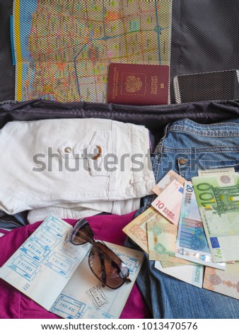 Money, passport and clothes in a suitcase for travel.