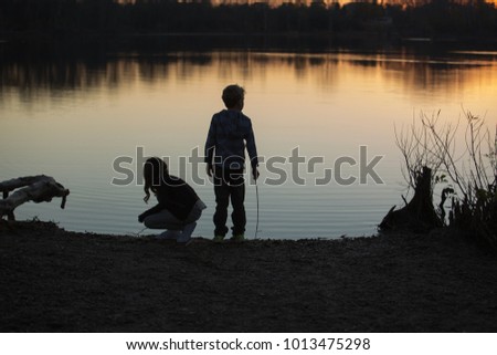 Silhouette of kids playing near the water on sunset