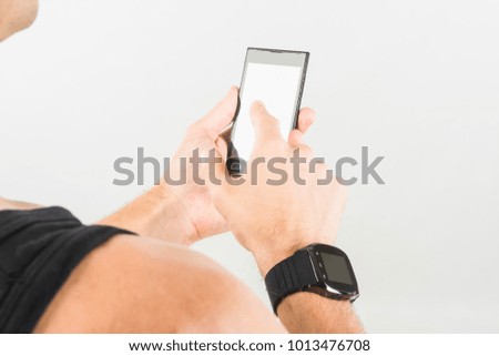 fitness man with black rubber smart watch and headset looks at smartphone isolated on white background
