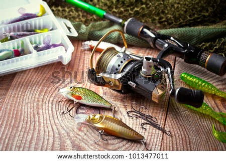 Fishing rods and spinnings in the composition with accessories for fishing on the old background on the table Royalty-Free Stock Photo #1013477011