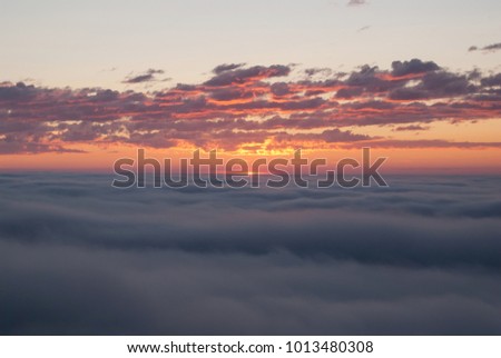 Orange and gray clouds over the misty plain