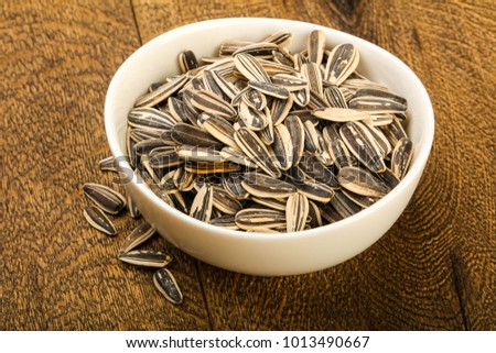 Sunflower seeds in the bowl over the wooden background