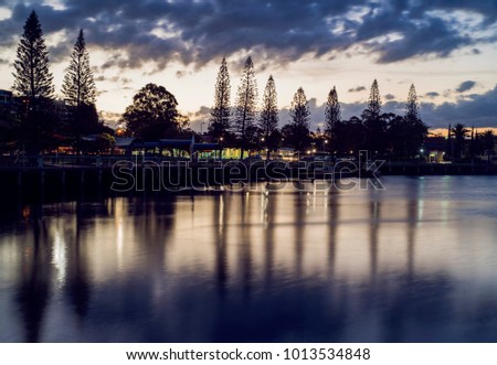 Sunset on harbour with trees and buildings in the background. Raby Bay Harbourside, Cleveland, Queensland, Australia.