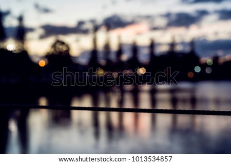 Selective focus of wire rail at sunset on harbour with trees and buildings in the background. Raby Bay Harbourside, Cleveland, Queensland, Australia.