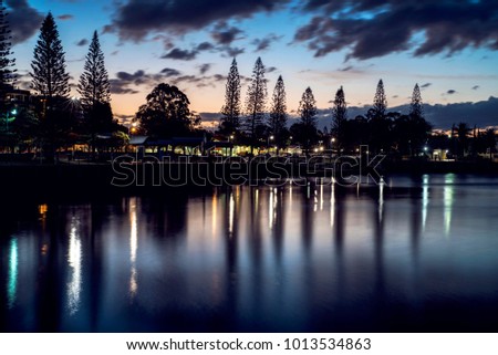 Sunset on harbour with trees and buildings in the background. Raby Bay Harbourside, Cleveland, Queensland, Australia.