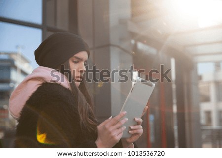 beautiful teenager woman using tablet pc computer outdoor on a city street. Horizontal shot.