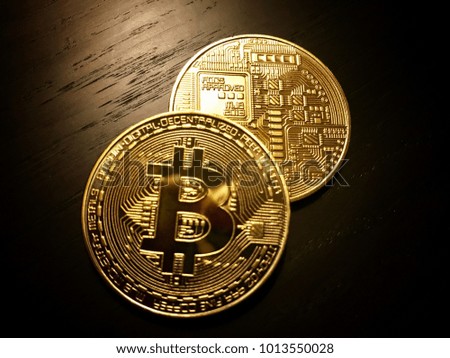 Front and back of golden bitcoins, the cryptocurrency on a dark wooden table