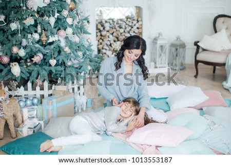 Happy girl with mother near Christmas tree