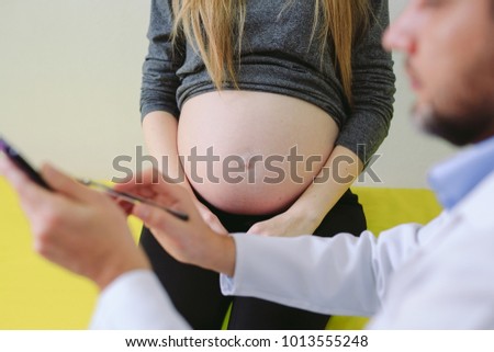 Gynecologist showing echo photo to pregnant woman.