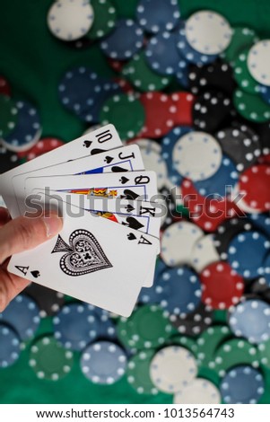 The player holds five playing cards in his hand. Royal Flash, card deck, poker royal flash on cards and poker chips on green casino table / on a black background. success in gambling. soft focus