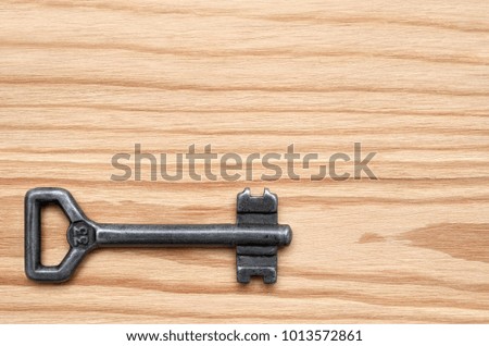 Key from the lock on the wooden background