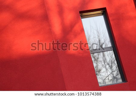 Close up view of a rectangular vertical window in a red wall. Isolated element on a painted surface. Detail of a colorful facade building and one window. Abstract urban picture. Minimalist figure.
