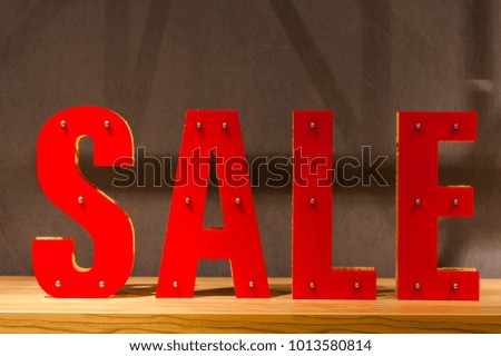 The inscription with red plastic letters "Sale" on a gray background on a wooden stand.