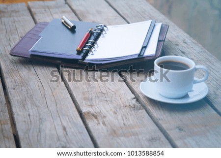 A wooden desk with coffee notebook and pen