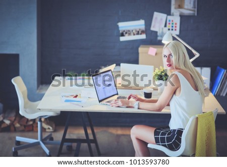 Fashion designers working in studio sitting on the desk.