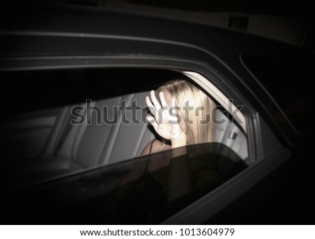 Paparazzi concept - invasion of privacy - young starlet blonde woman blocking her face while being photographed in a black limousine 