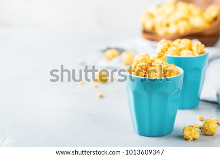 Junk sweet food concept. Caramel popcorn in blue glasses ready for party and cinema. Copy space background