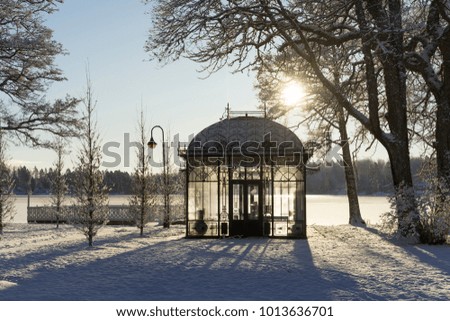 Beautiful nature and landscape photo of cold sunny winter day in Sweden Scandinavia. Nice clear blue sky at morning. Snow, small glass house and ice lake. Calm, peaceful and happy outdoors image. 
