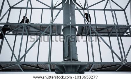 The steel frame construction of large banner. Industrial climber hangs a poster on a billboard. workers installing metal sheets on big billboard