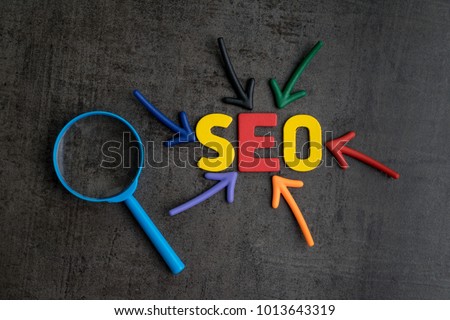 SEO, Search Engine Optimization ranking concept, magnifying glass with arrows pointing to alphabets abbreviation SEO at the center of cement wall chalkboard, the idea of promote traffic to website. Royalty-Free Stock Photo #1013643319
