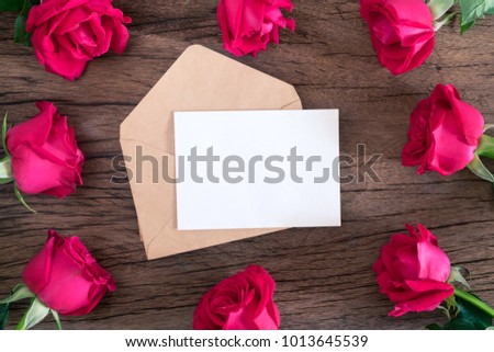 Gift card with beautiful red roses on wooden background