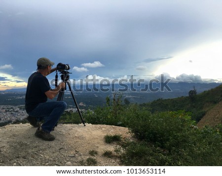 photographer's life, captures moments of nature on top of mountains, his lifestyle, passionate about photography and cameraman,
his camera mounted on tripod