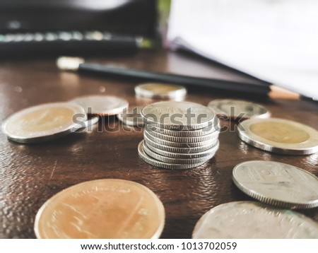 pile Coin and Have a pencil behind the image..Put on a wooden table.Stacks of different coins placed in a row.Thai Baht.business and investment. Use As Business , Saving money And Finance Concept.