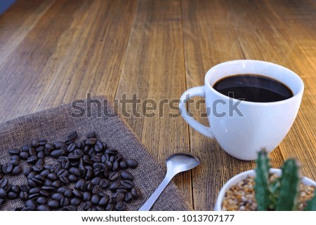  Hot coffee cup and coffee beans on wooden table                              