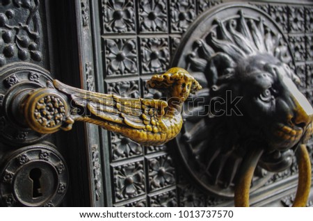 Old forged door with lion ring knock knocker. Gamayun