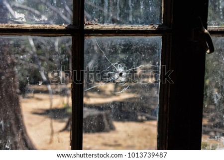 Bullet hole in a window of an abandoned building Royalty-Free Stock Photo #1013739487