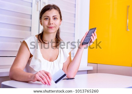 Young attractive girl with smartphone and plastic credit card in hand. Online payments in online store from the phone. Modern payments in mobile device.