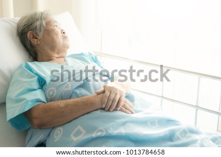 Elderly patient alone in bed. Alone and stress, missing her grand children. Looking at window. Very senior, old chinese woman. Royalty-Free Stock Photo #1013784658
