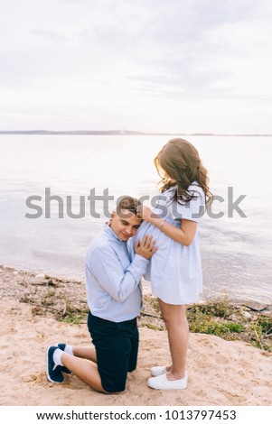 Happy and young pregnant couple hugging in nature
