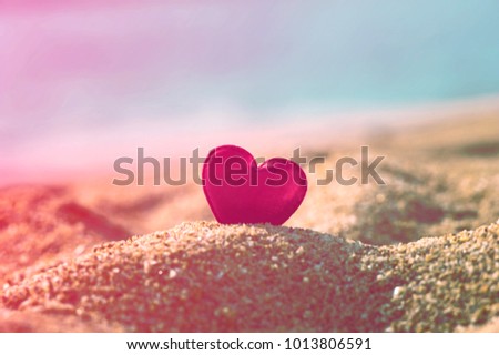 Pink fabric heart on golden sand, beautiful postcard background 