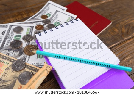 Dollars and passport lying on wooden table. Notepad to plan. Copy paste