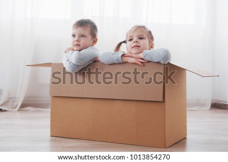 Two a little kids boy and girl playing in cardboard boxes. Concept photo. Children have fun.