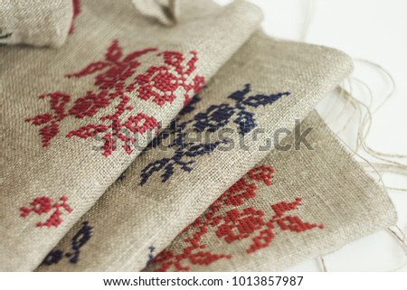 Billets of linen fabric with embroidered ornament on a light background. Close-up