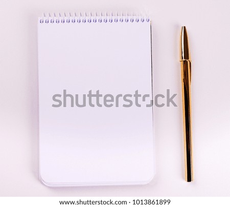 Notepad with blank paper next to golden ball pen on white background. Isolated. Mockup.