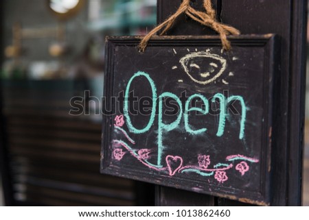 Cafe shop sign says we are "open" and write with chalkboard.