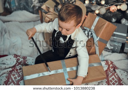 A boy in a tuxedo opens gifts. Box with gifts close-up