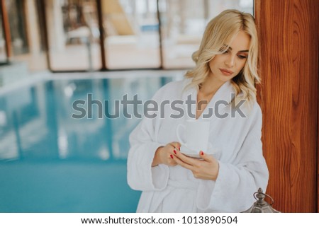 Pretty young woman relaxing by swimming pool in spa center