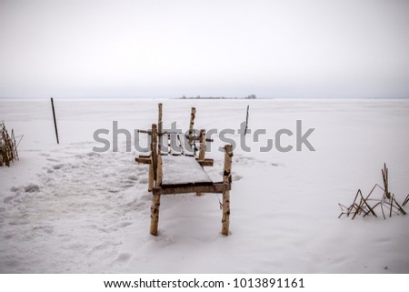 Photo of bench made of birch logs, snowy field during day