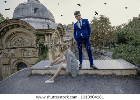 A photo shoot of a guy in a blue suit, a girl in a pink dress