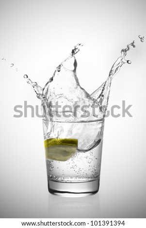 Lemon slice making a great soda splash in a glass with white background.