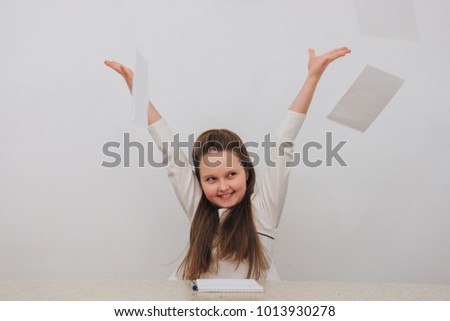 Young happy girl throwing up sheets of paper with gray background.