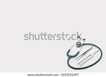 green stethoscope and doctor tools tuning fork  forceps on isolated white background with copy text space