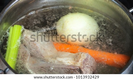 cooking soup - boiling beef stock in stewpan close up